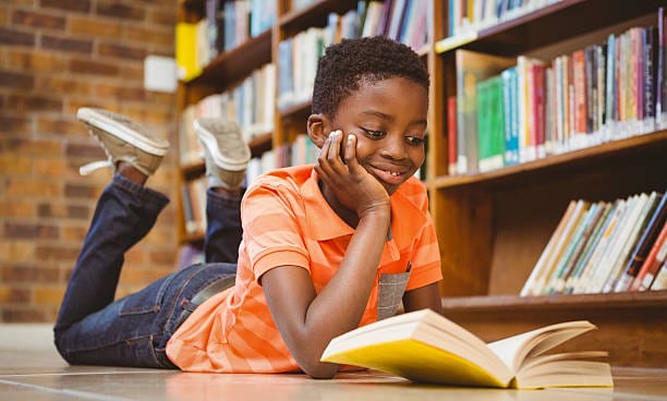 Cute little boy reading book in the library