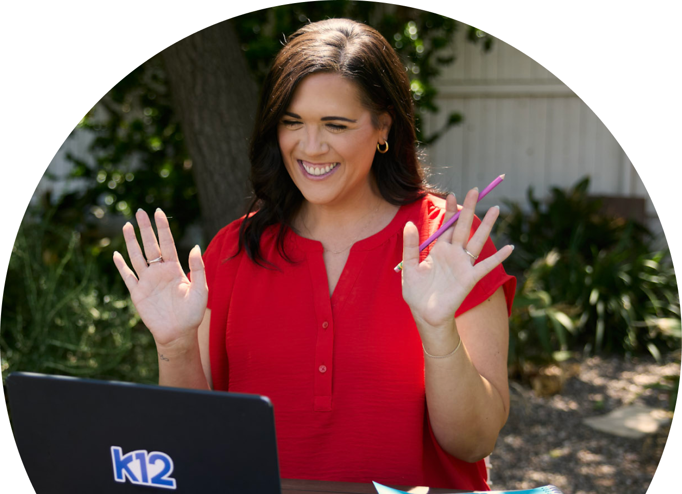 Teacher wearing a red shirt saying hi to her online class
